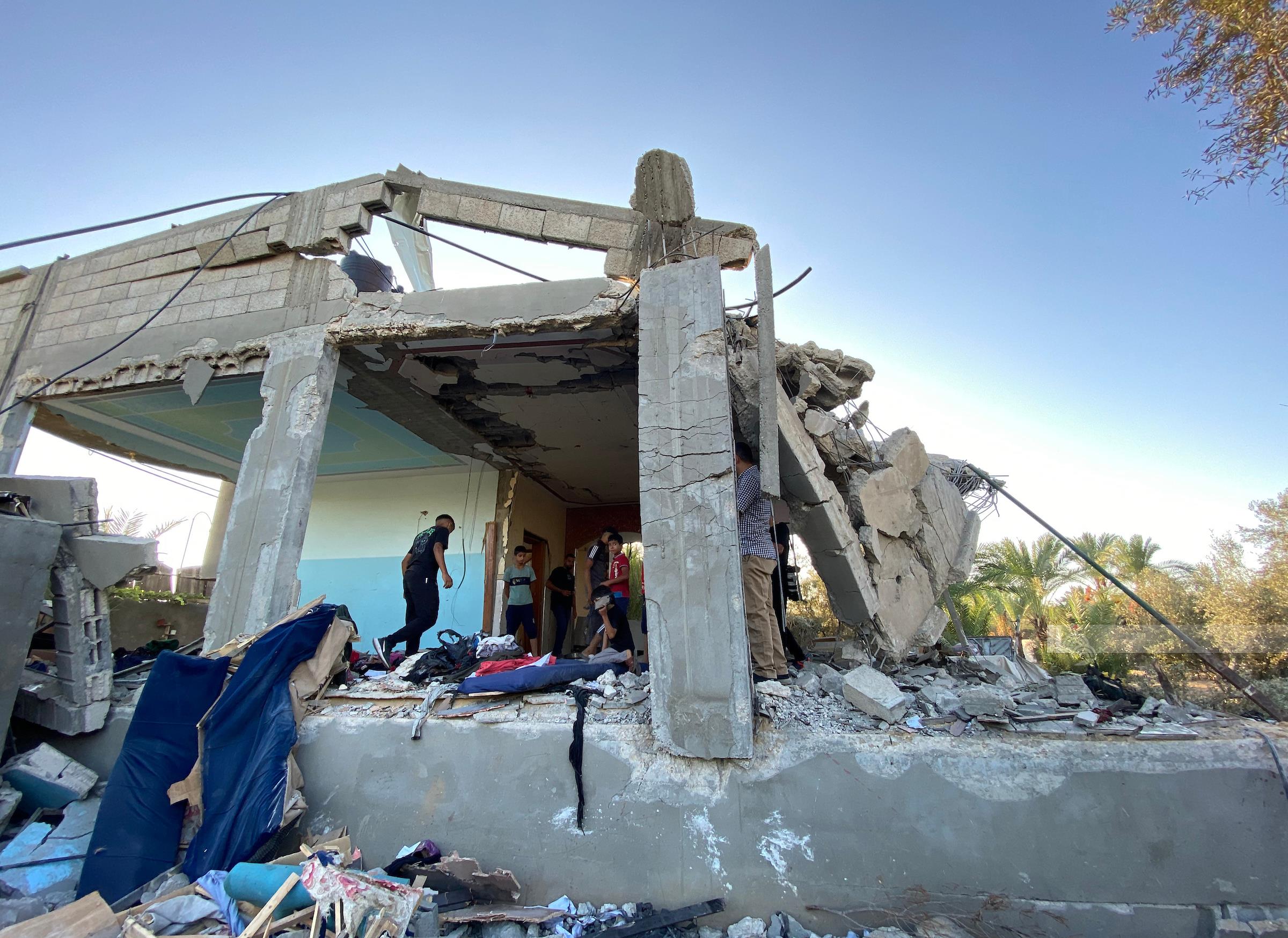 مواطنون يتفقدون الدمار جراء قصف طائرات الاحتلال الإسرائيلي منزلا في دير البلح وسط قطاع غزة (وفا)